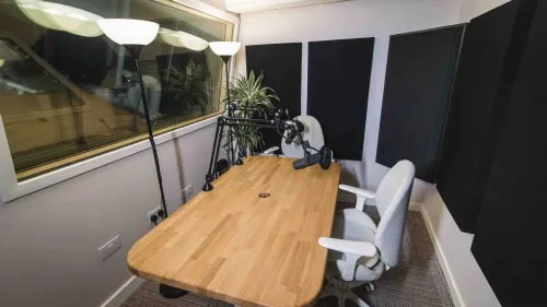 Two modern white chairs in a sound proof room, set up with desk mounted microphones